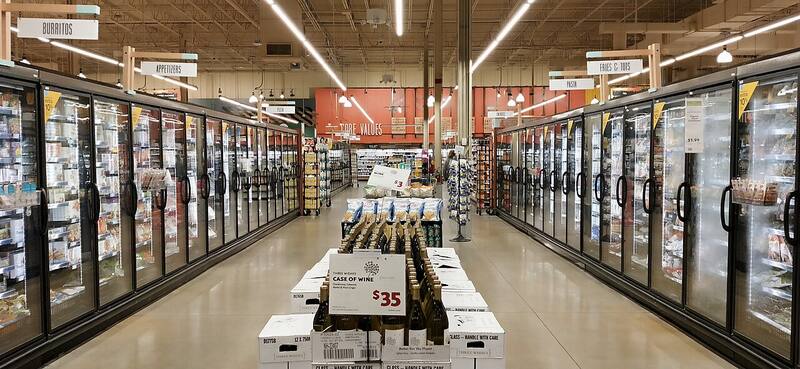 Supermarket aisle lined with glass-door refrigerated display cabinets