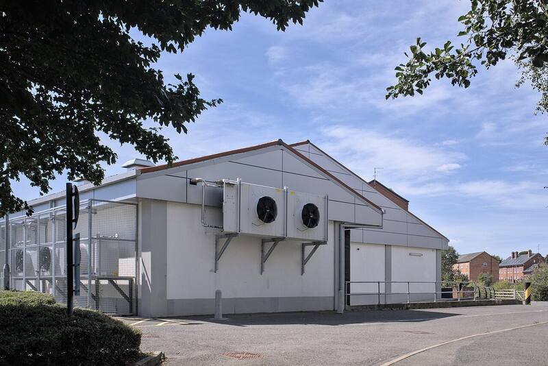 Wall-mounted commercial refrigeration condensing units on the side of a commercial building